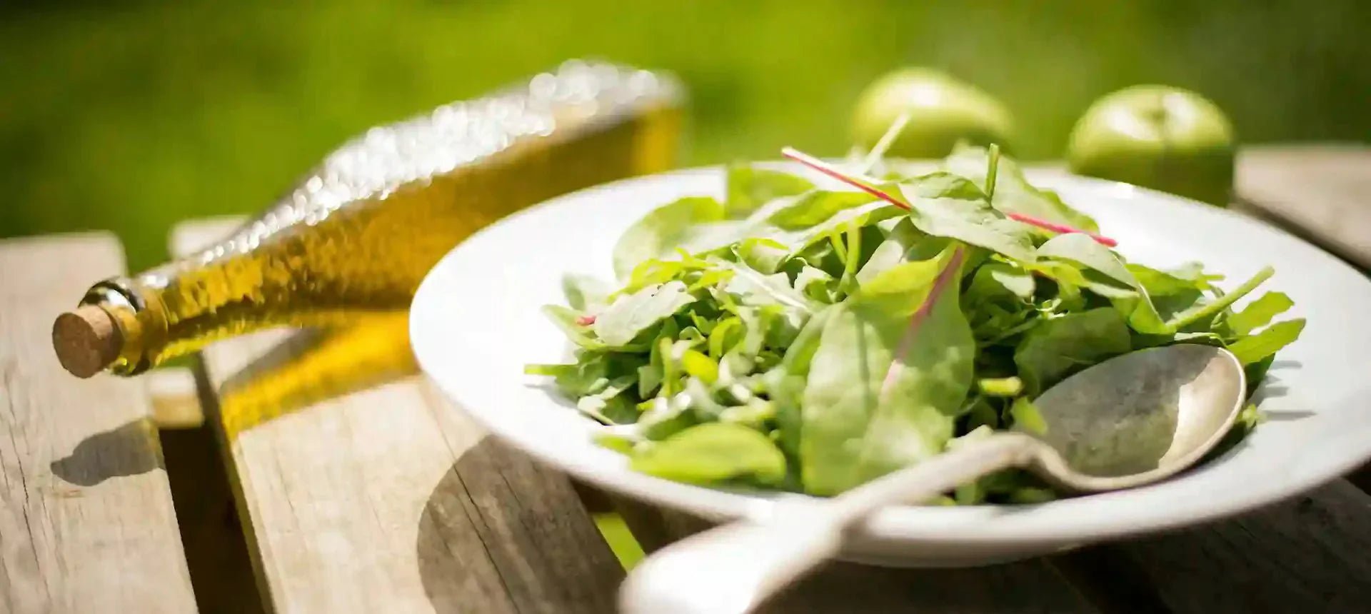 Composición fotográfica de una ensalada en exterior con una botella de aceite