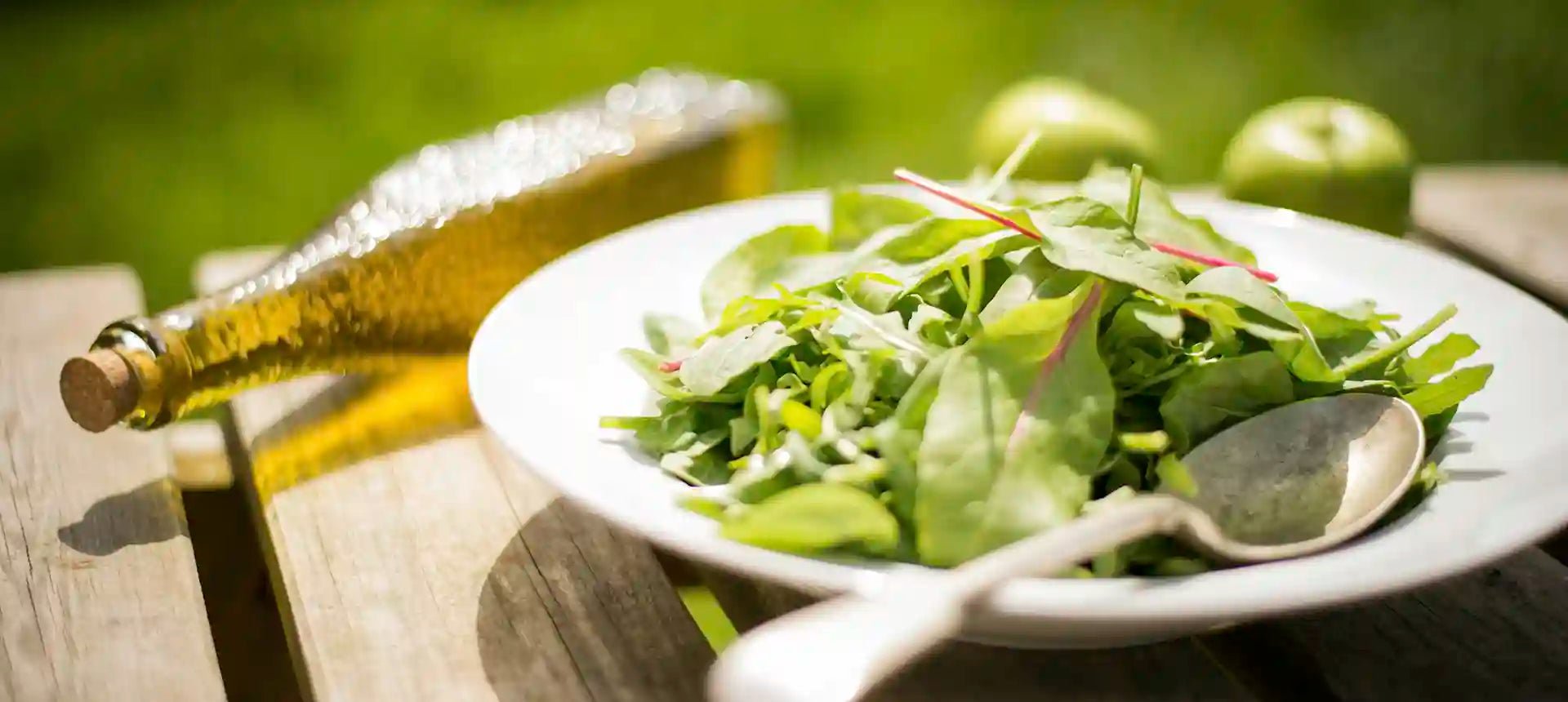 Composición fotográfica de una ensalada en exterior con una botella de aceite