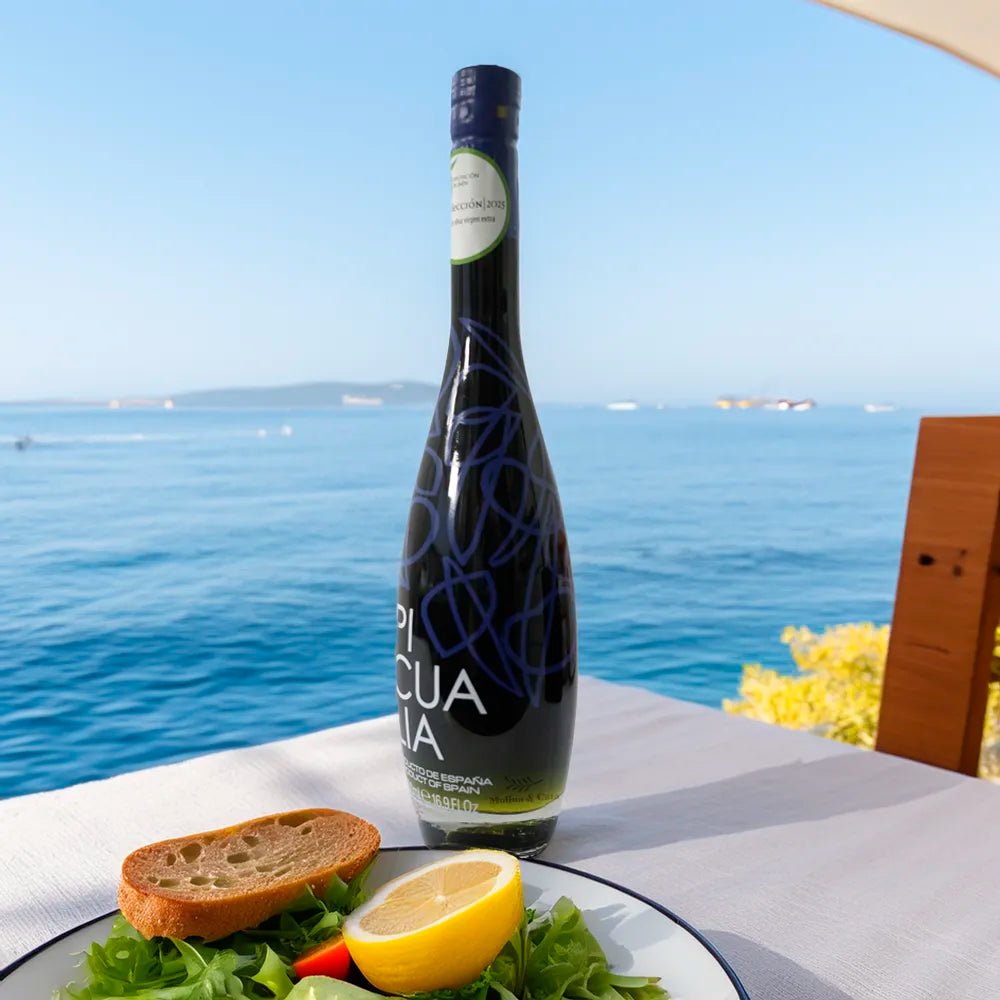 Botella de aceite de oliva virgen extra Picualia Reserva 500ml en mesa de restaurante al borde del mar mediterráneo