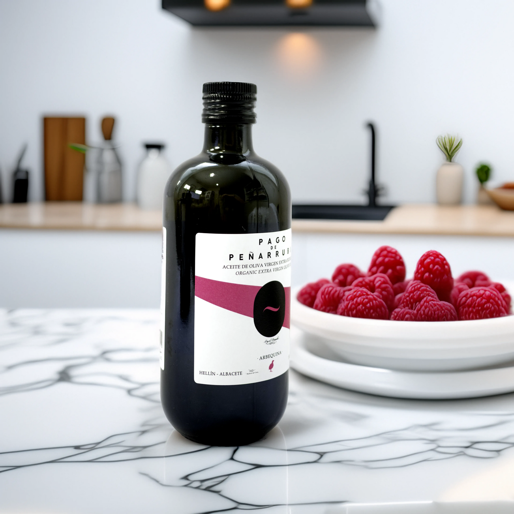 Pago de Peñarrubia Aceite de Oliva Virgen Extra Ecológico Arbequina 500ml en una cocina moderna de mármol con un plato de frambuesas